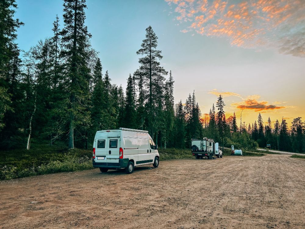 Camper parcheggiati lungo una strada sterrata in Lapponia, difronte un bel tramonto finlandese