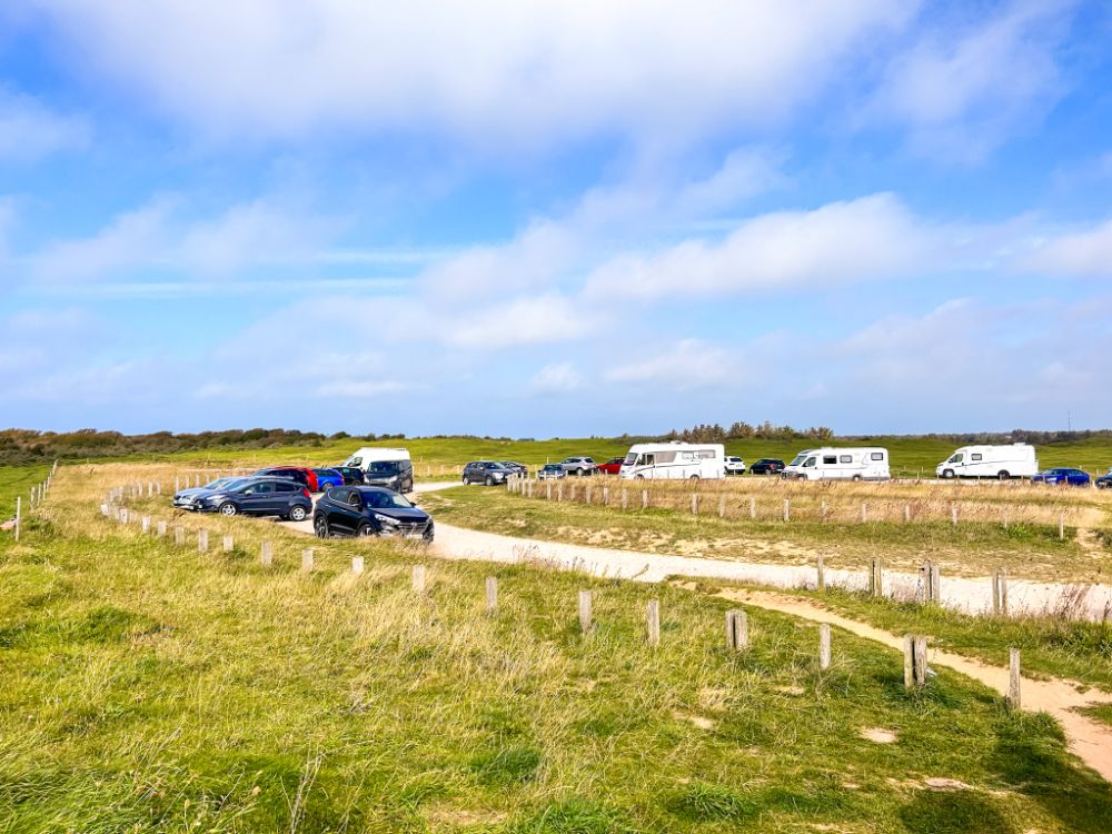 Pianura danese, una strada bianca con auto e camper posteggiati.